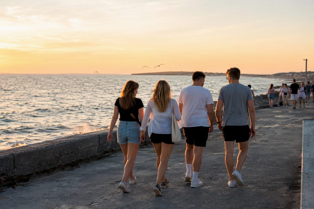 Group walking on Salthill promenade at sunset