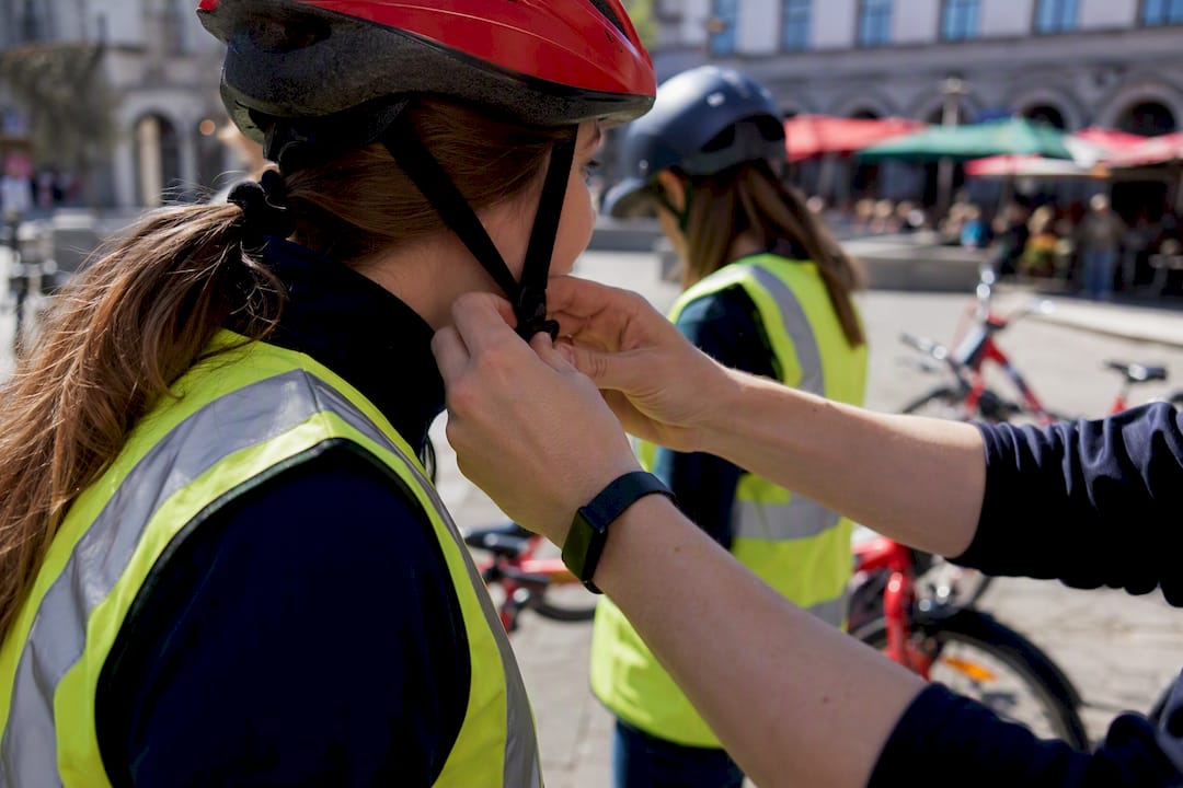 Hands adjusting bike helmets and safety gear outdoors