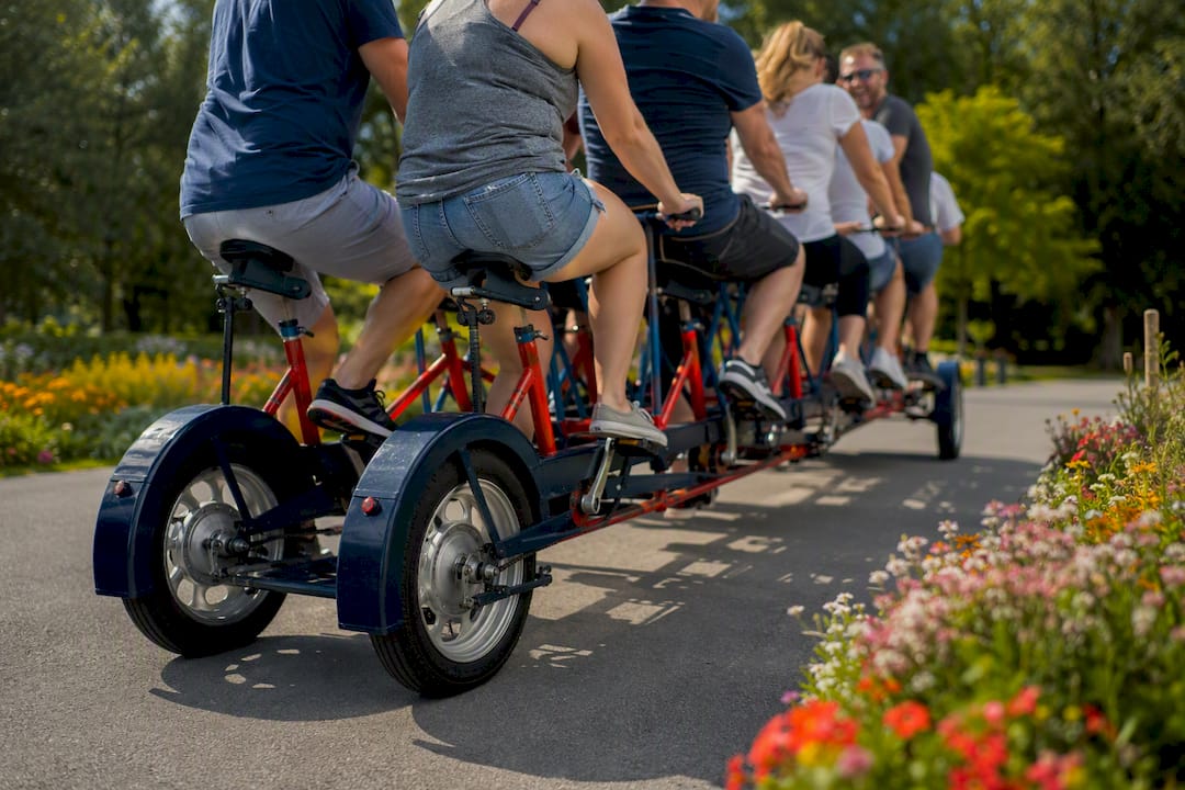 Group pedaling team bike outdoors in Galway park