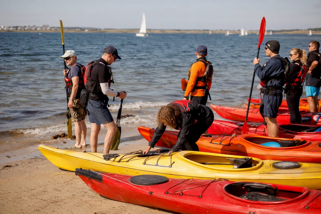 Group preparing kayaks on Galway Bay shore