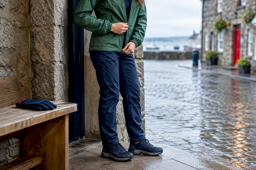 Rider fastening jacket above wet cobblestones