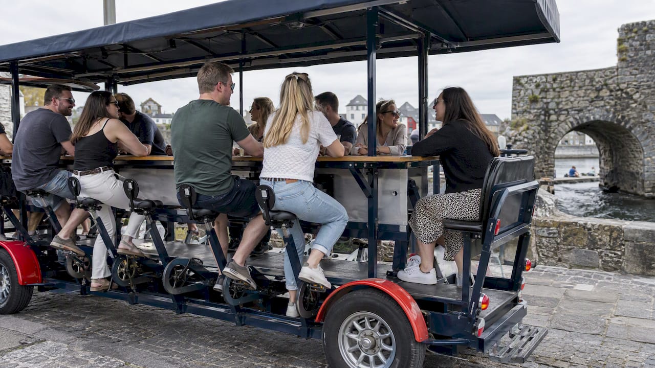 Passenger seated while others pedal the party bike